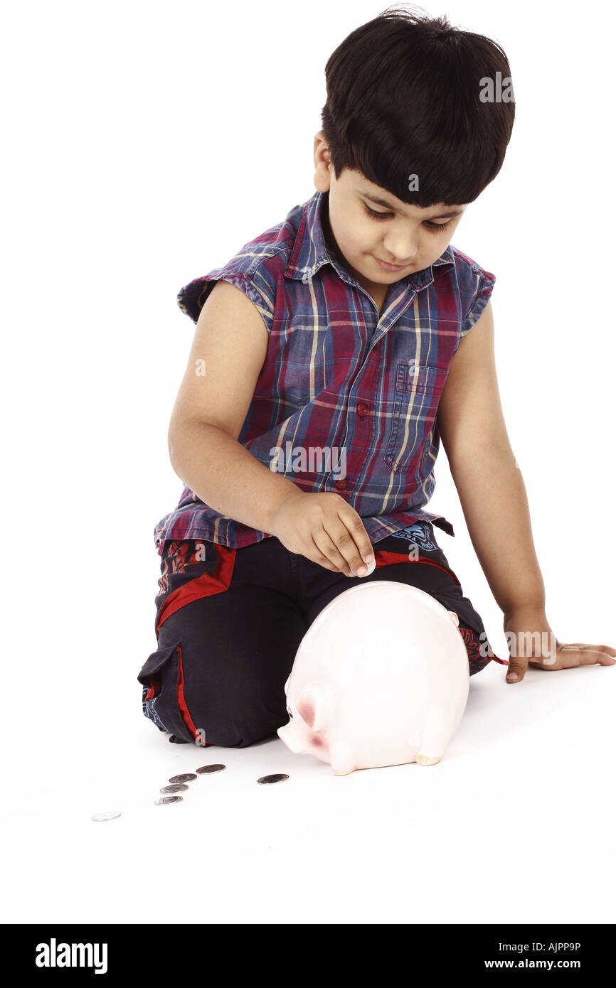 Portrait of a boy putting coins into a piggy bank Stock Photo - Alamy