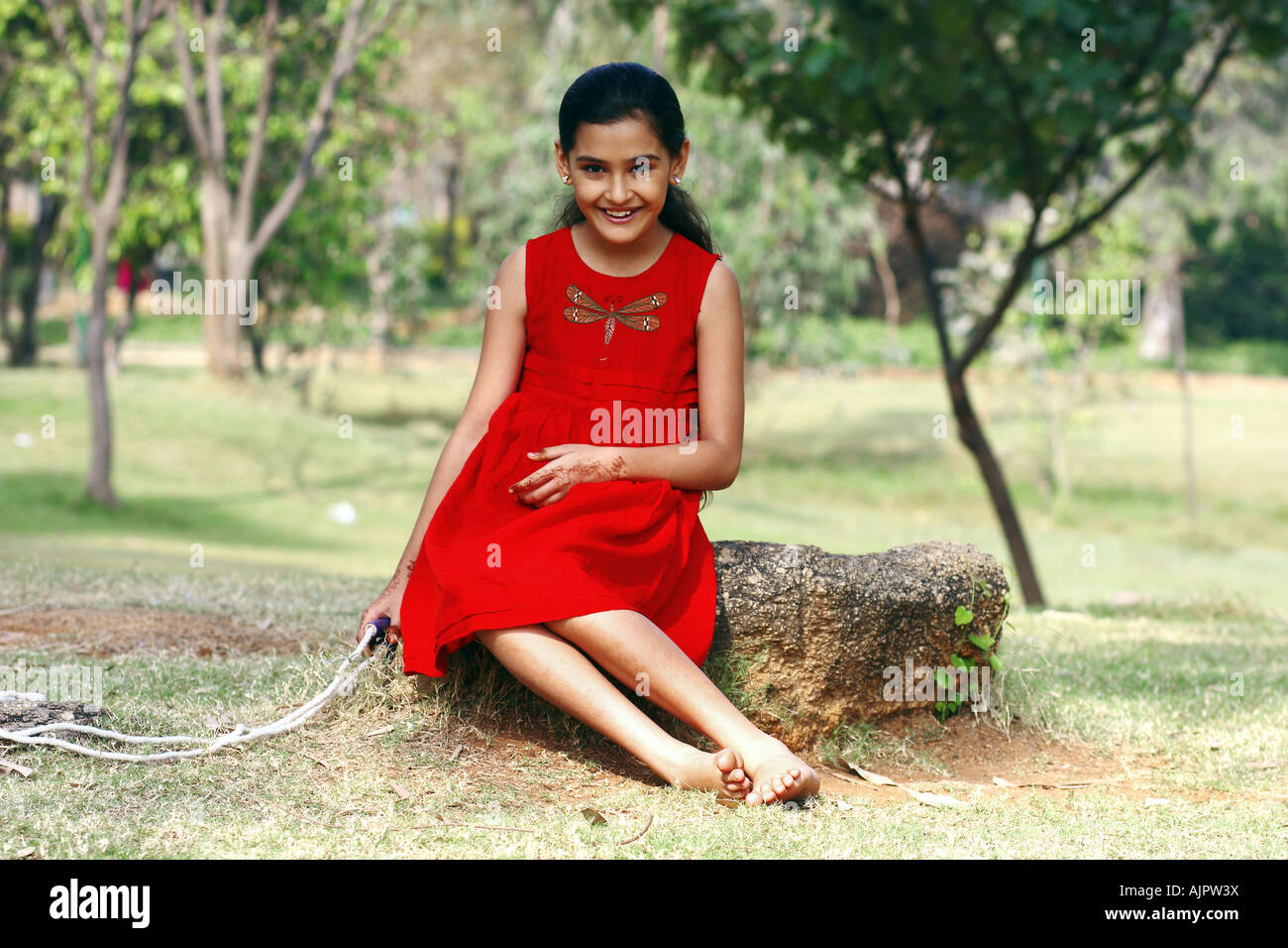 Portrait of a young girl sitting in a park Stock Photo - Alamy