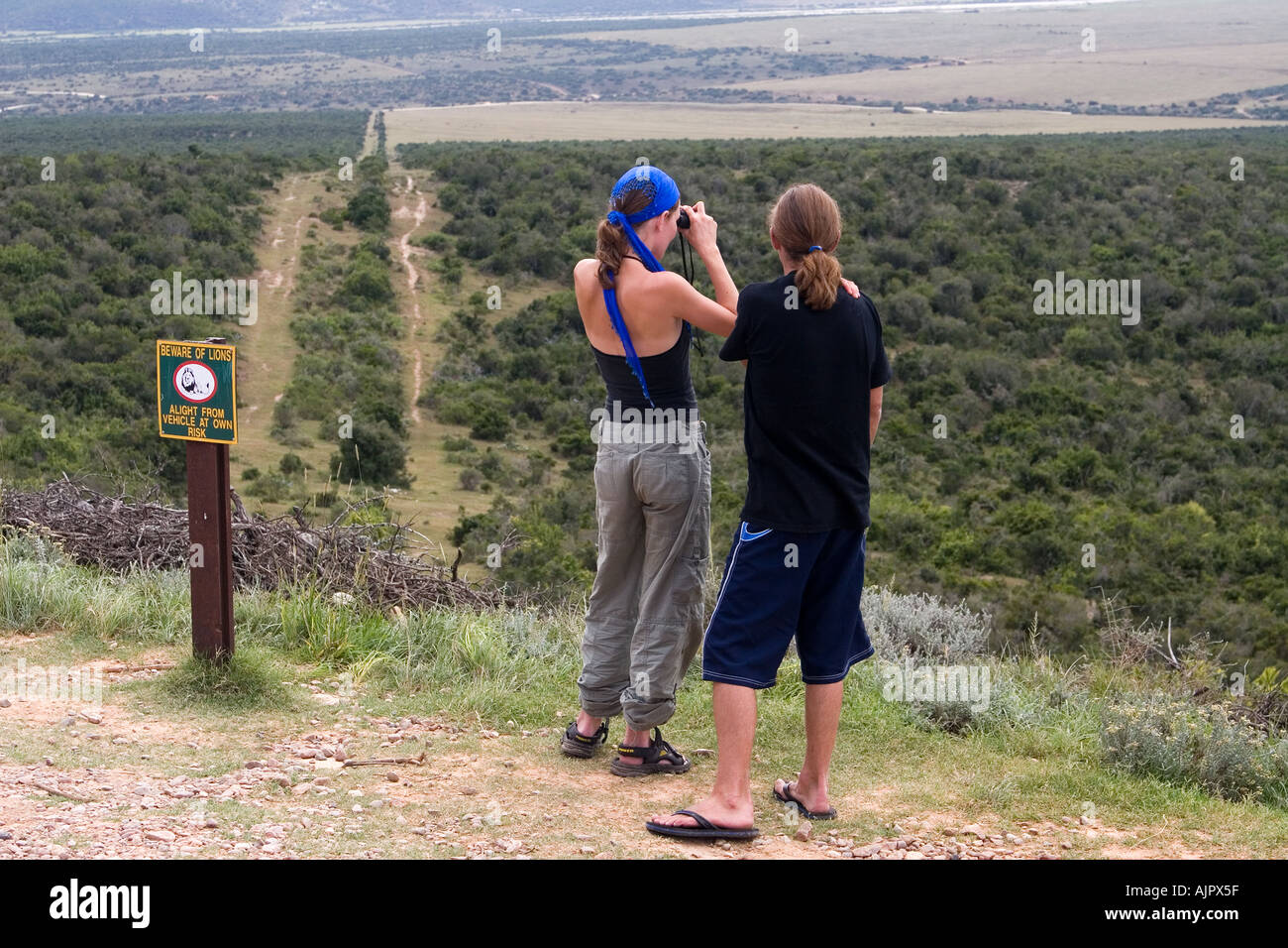 south africa Addo Elephant National Park viewpoint beware of lions sign tourist couple with binaculars Stock Photo