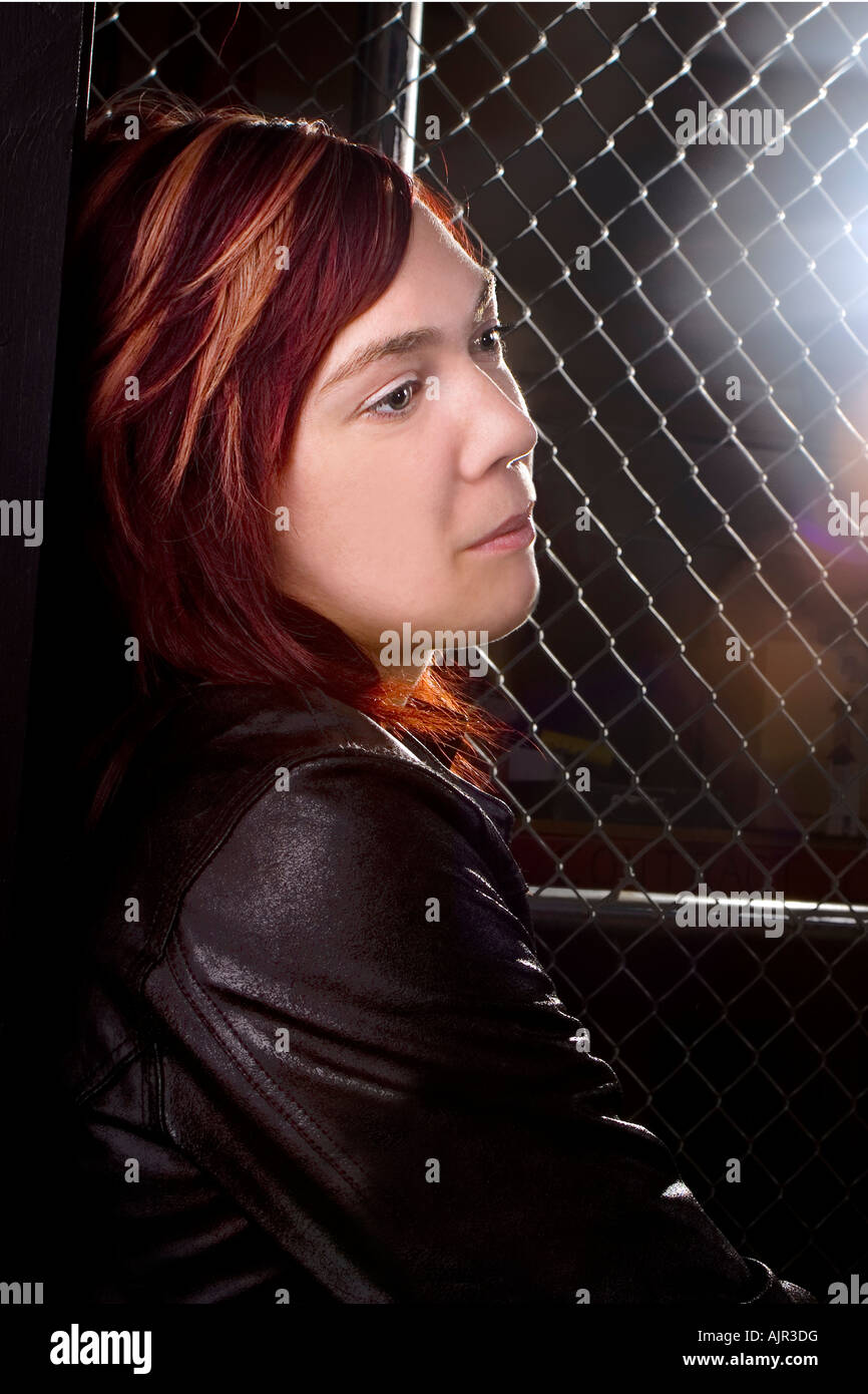 Young woman standing along chain link fence Stock Photo