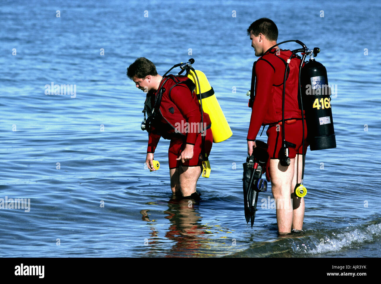 Two mem in scuba gear prepare to dive from shore Stock Photo Alamy