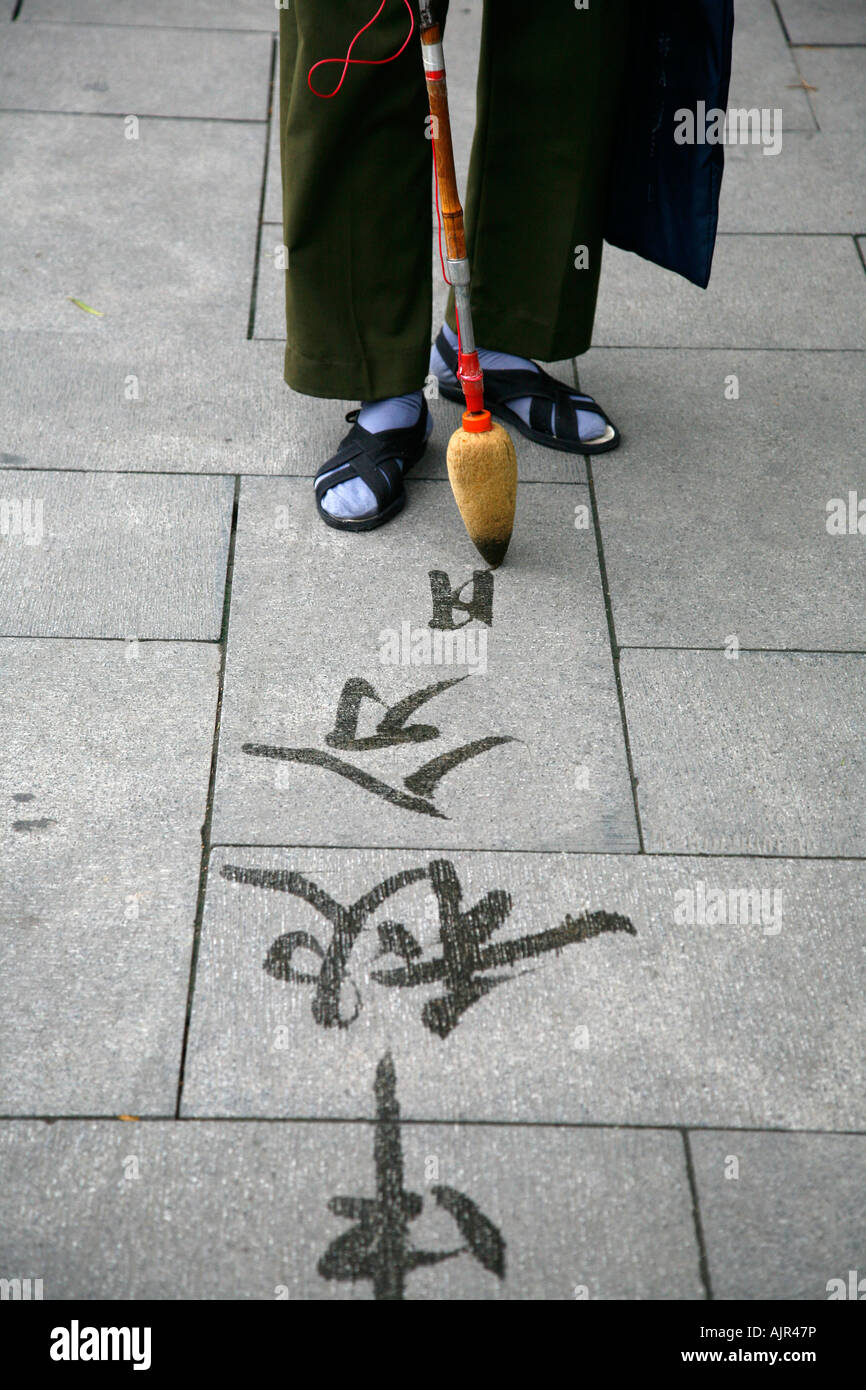 Man writing calligraphy on the ground with water brush at Beihai Park Beijing China Stock Photo