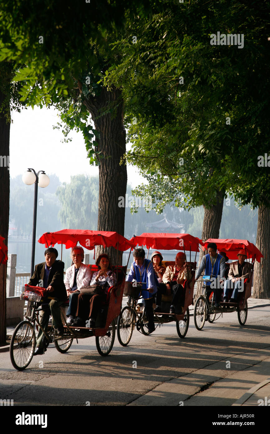 Rickshaw drivers taking tourist on a tour in the Houhai lakes area Beijing China Stock Photo