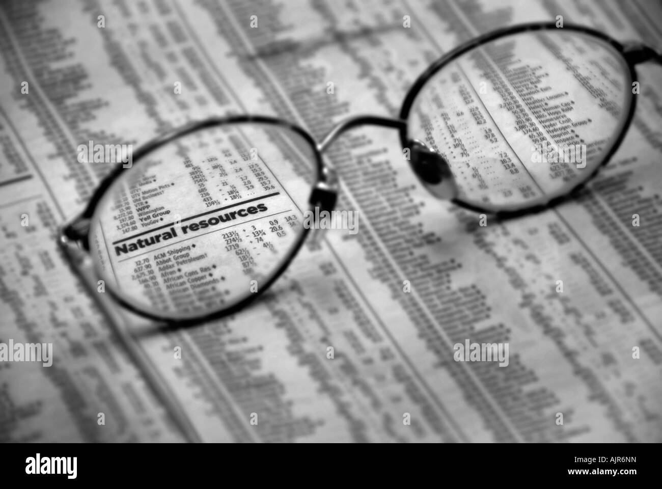 Reading glasses placed on  news paper with focus on newspaper print reading Natural Resources Stock Photo