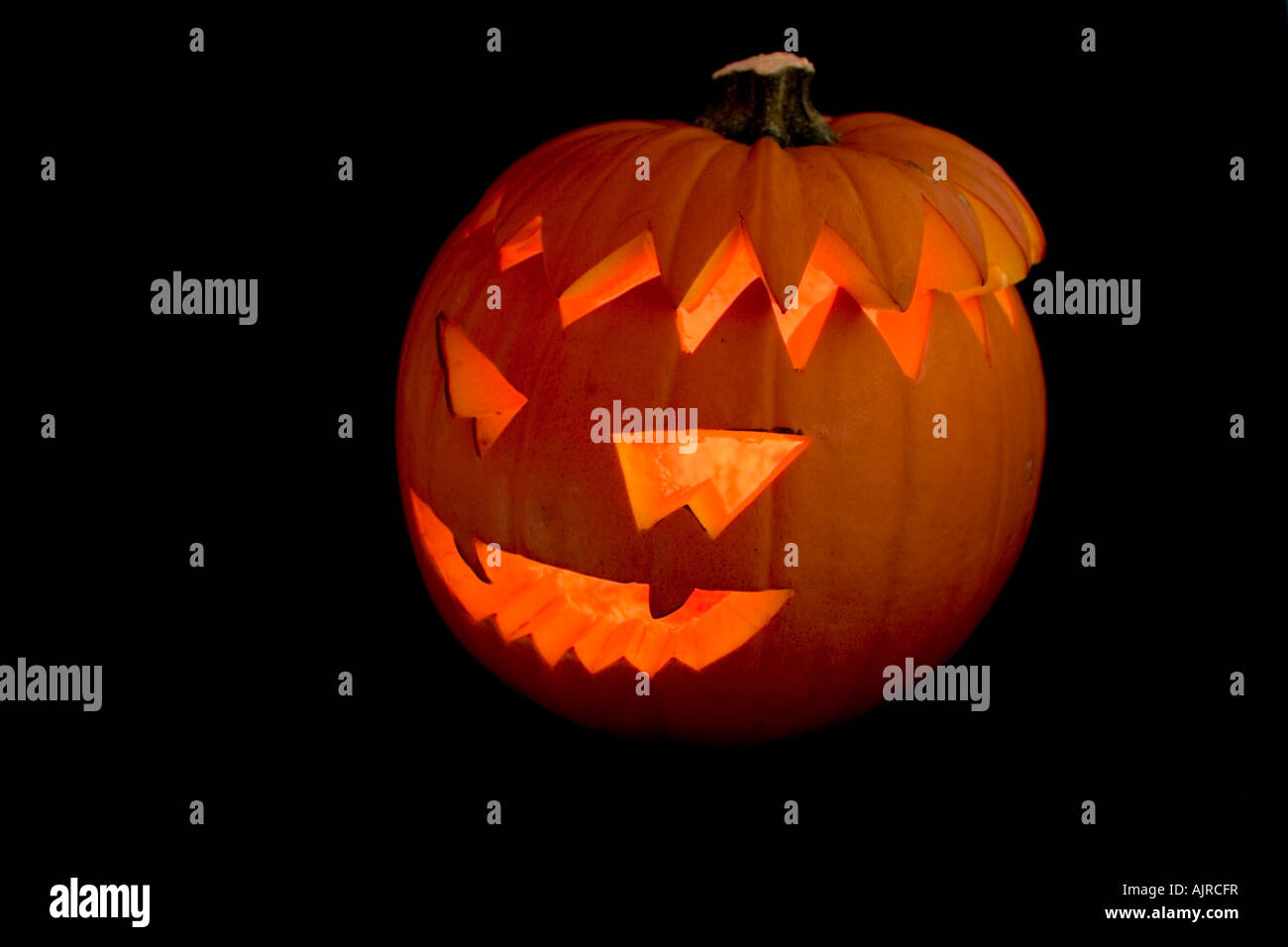 Halloween Orange pumpkin head lit by candle on a black background Stock Photo