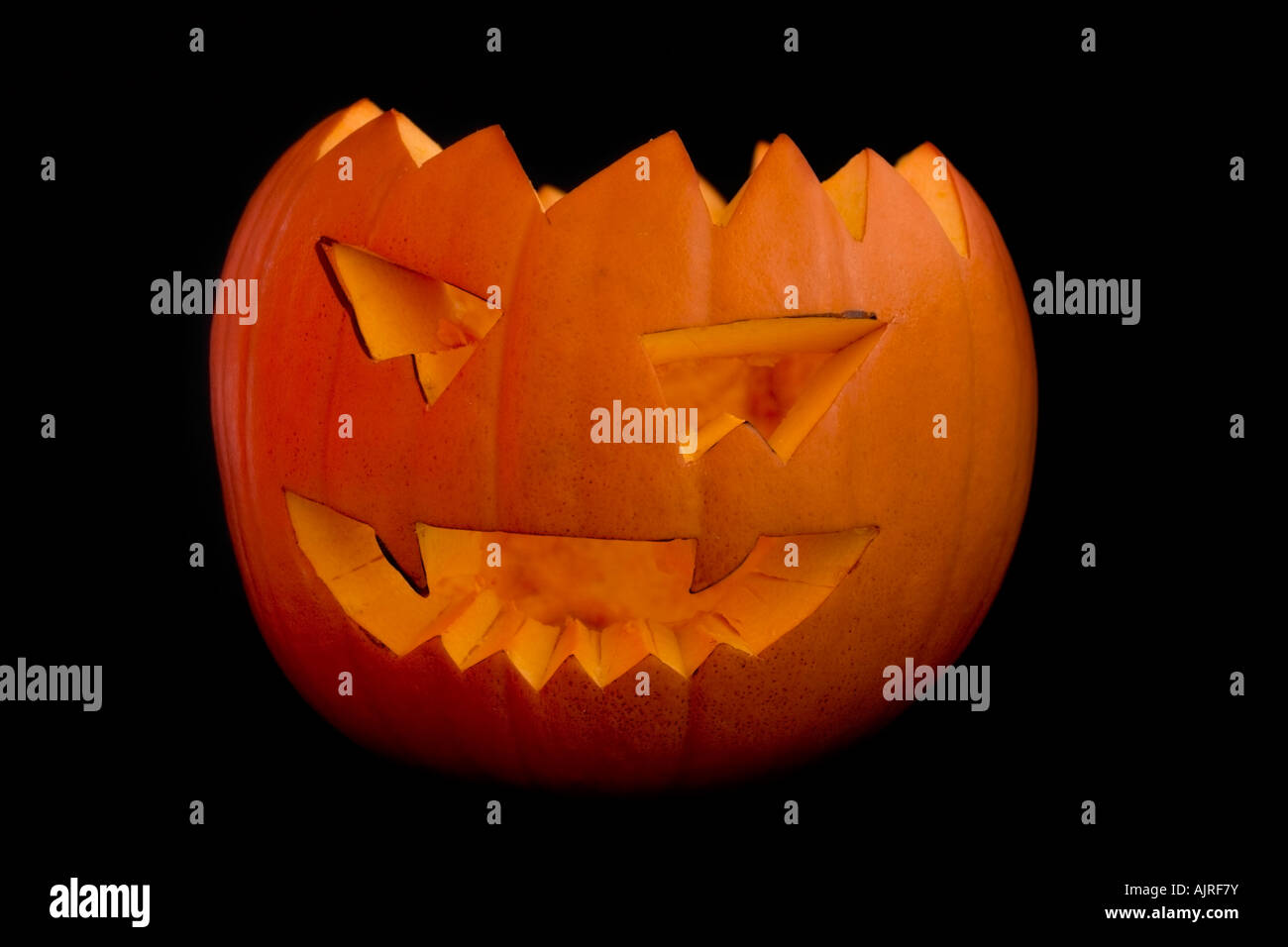 Halloween Orange pumpkin head lit by candle on a black background Stock Photo