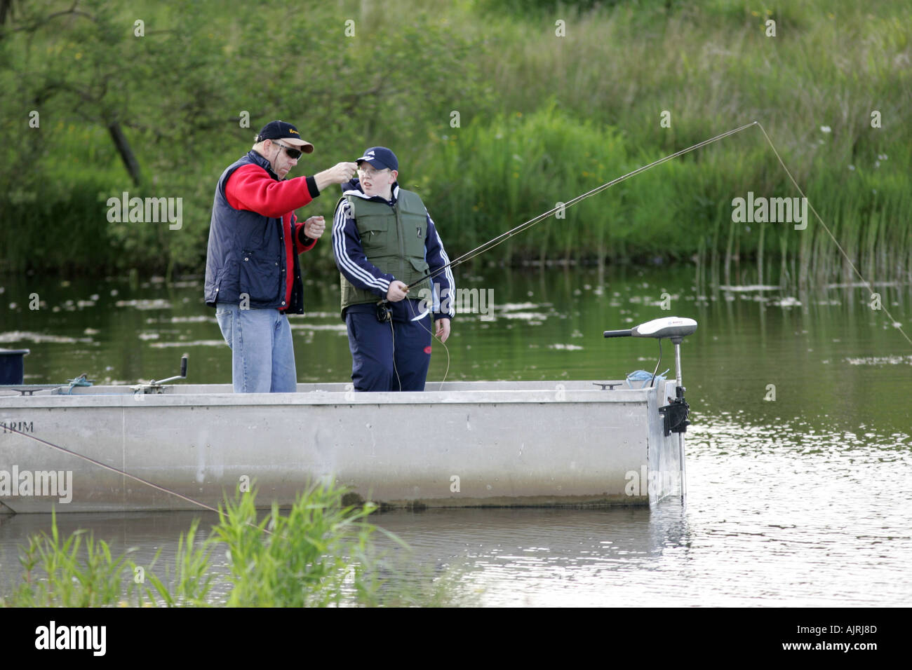 Instructor in boat teaching youth to fly fish Tildarg fishery county antrim northern ireland Stock Photo