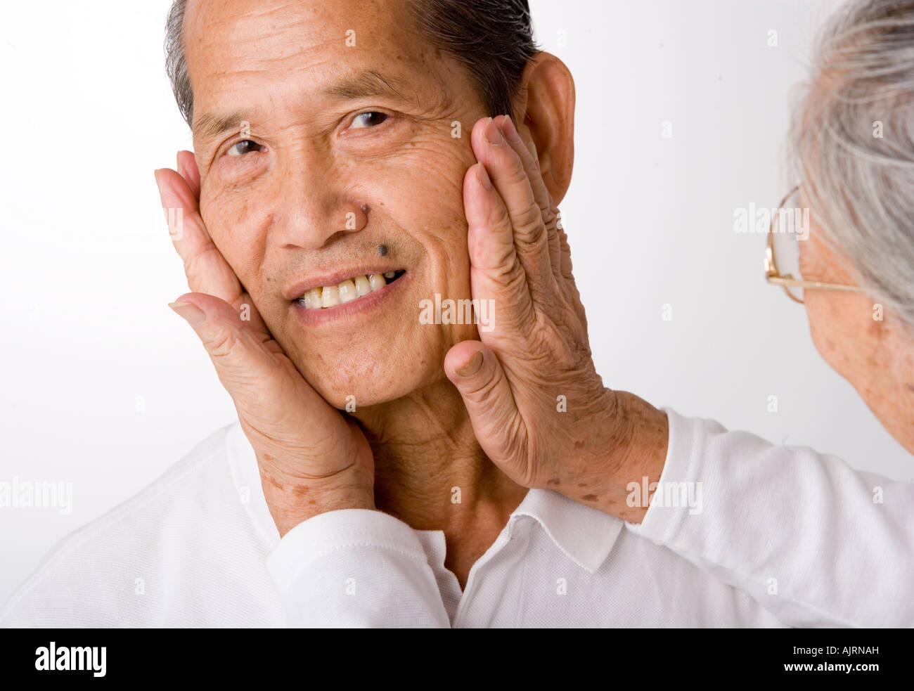 Close-up of a senior woman holding a senior man's face in her hands Stock Photo