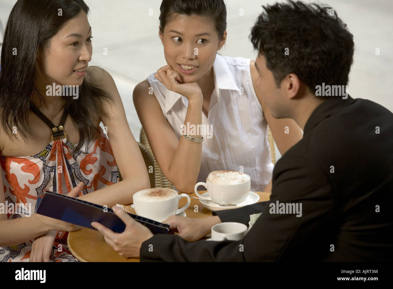 Rear view of a young man with two young women Stock Photo - Alamy