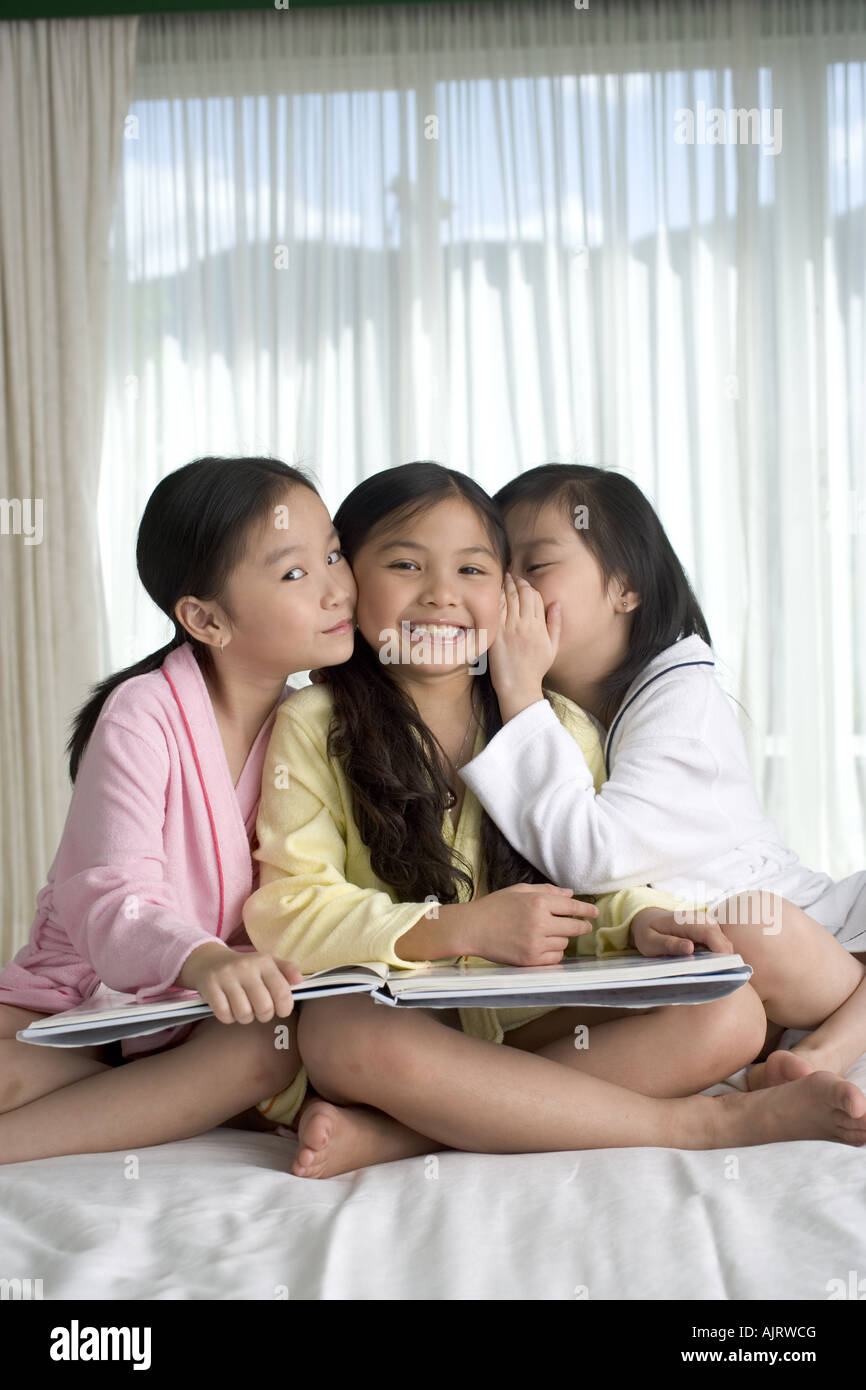 Portrait of two girls smiling with a girl whispering Stock Photo - Alamy
