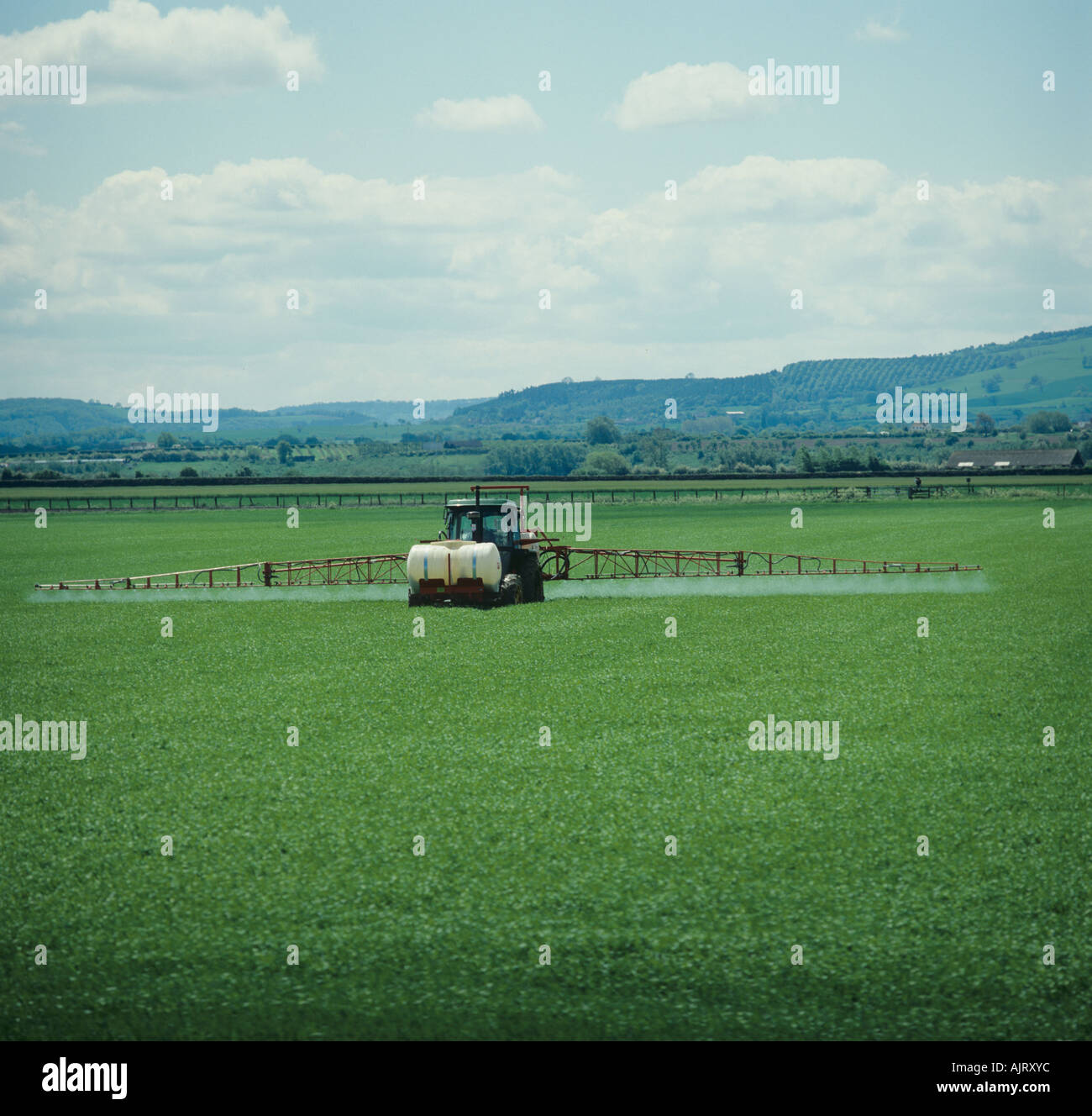 John Deere tractor with large boom sprayer spraying wheat crop in spring Stock Photo