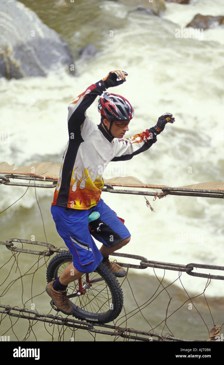Unicyclist crossing rope bridge on unicycle Stock Photo Alamy