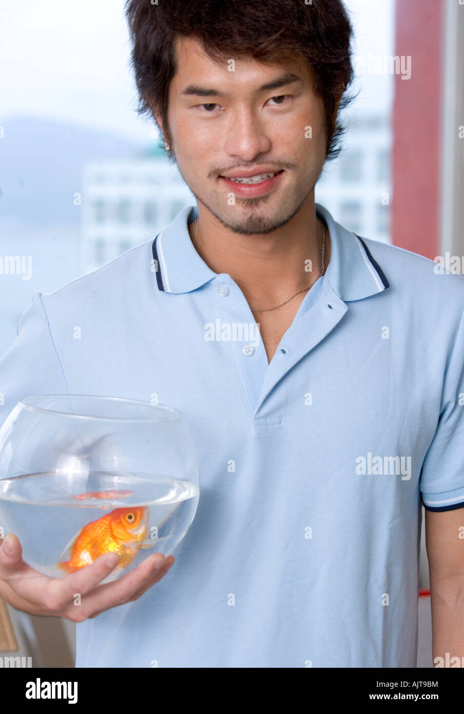 Portrait of a young man holding a fish bowl and smiling Stock Photo Alamy