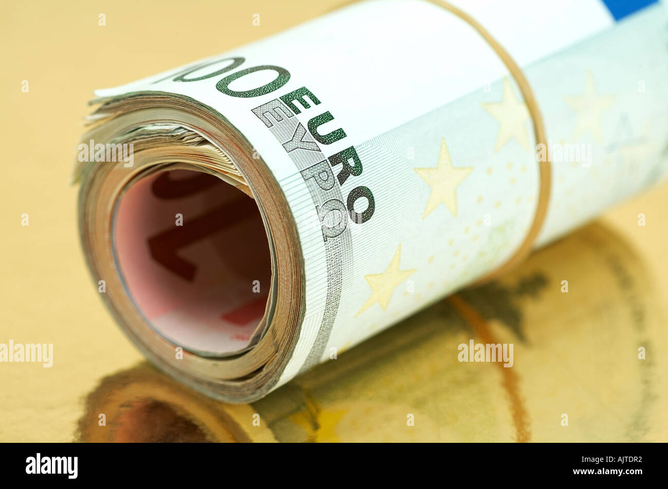 Roll of Euro banknotes on golden background Stock Photo - Alamy