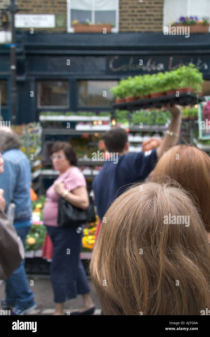 Veiw from behind the back of a woman s head of people shopping for flowers in Colobia road market in the East End of London Stock Photo