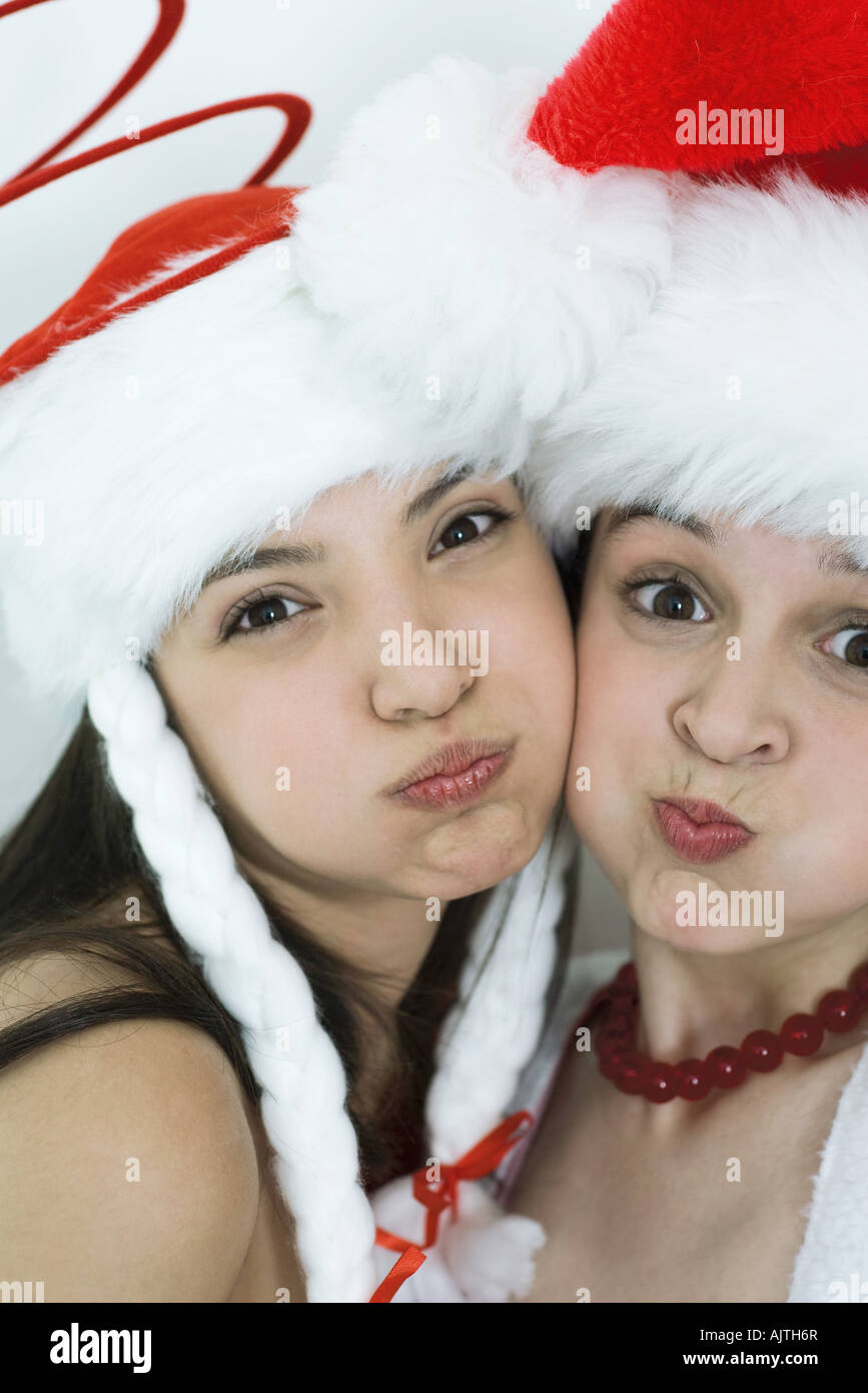 Two young female friends dressed in Christmas costumes, puffing out cheeks, looking at camera, portrait Stock Photo