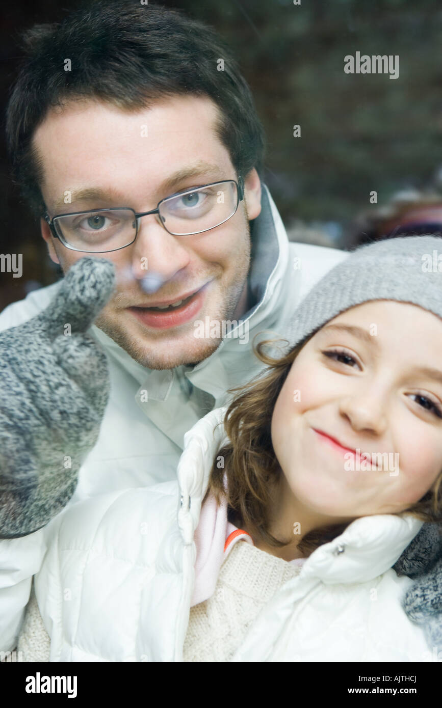 Young man looking over little sister's shoulder and pointing, both smiling at camera, portrait Stock Photo