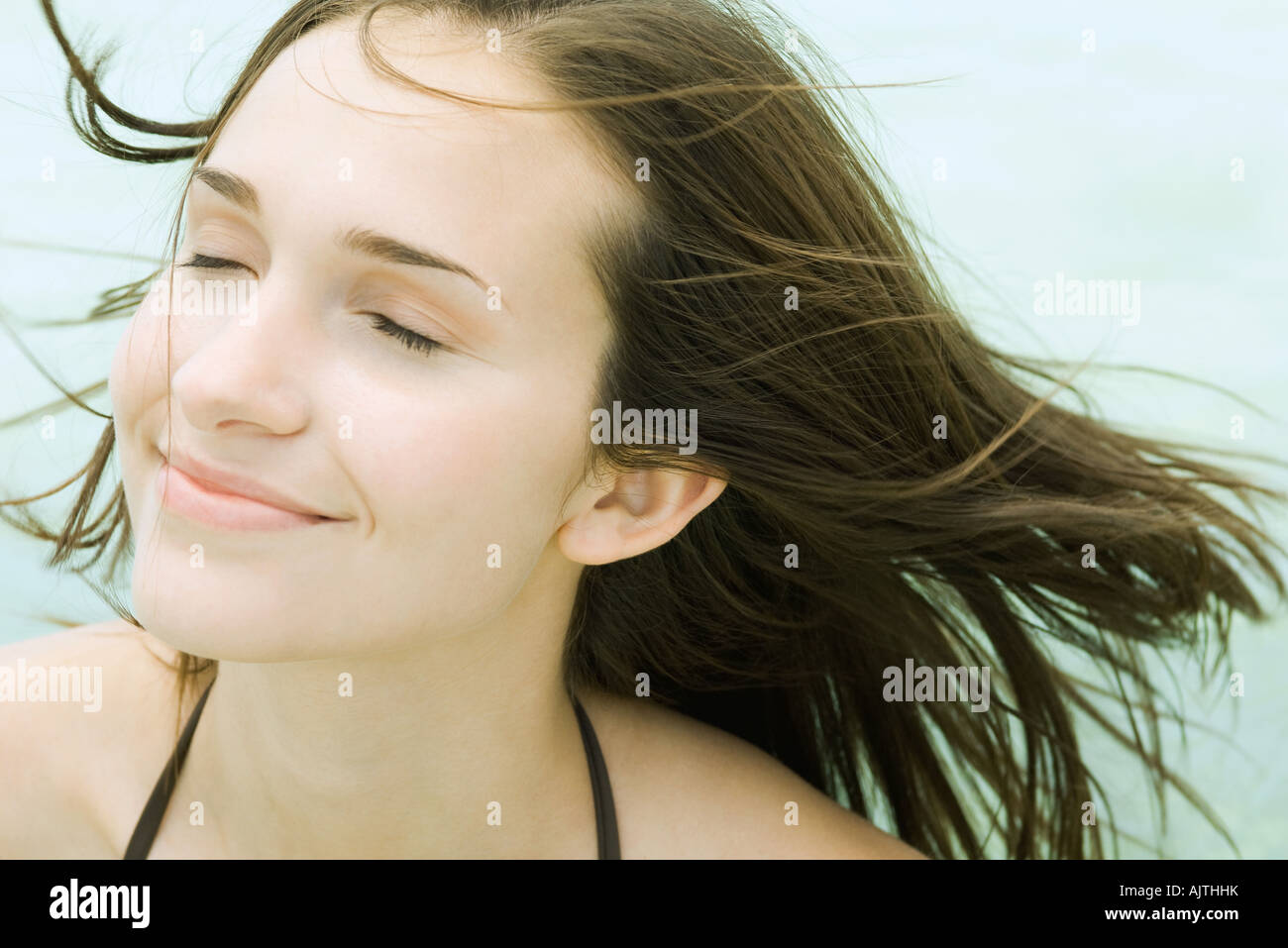 Young woman smiling, eyes closed, hair blowing in breeze, portrait Stock Photo
