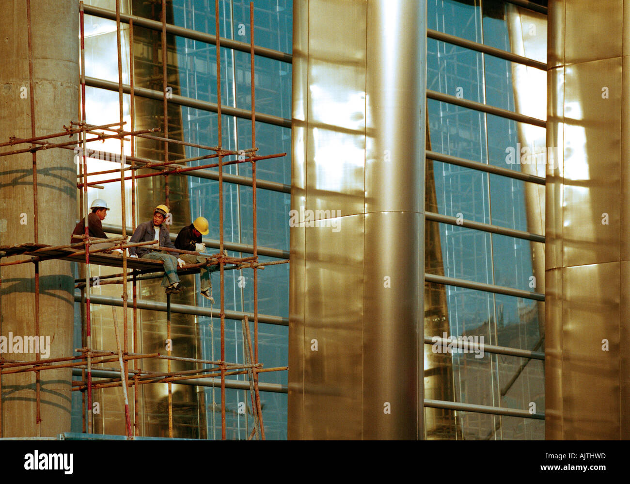 Workers taking a break and eating lunch against a modern office development, Beijing. Stock Photo