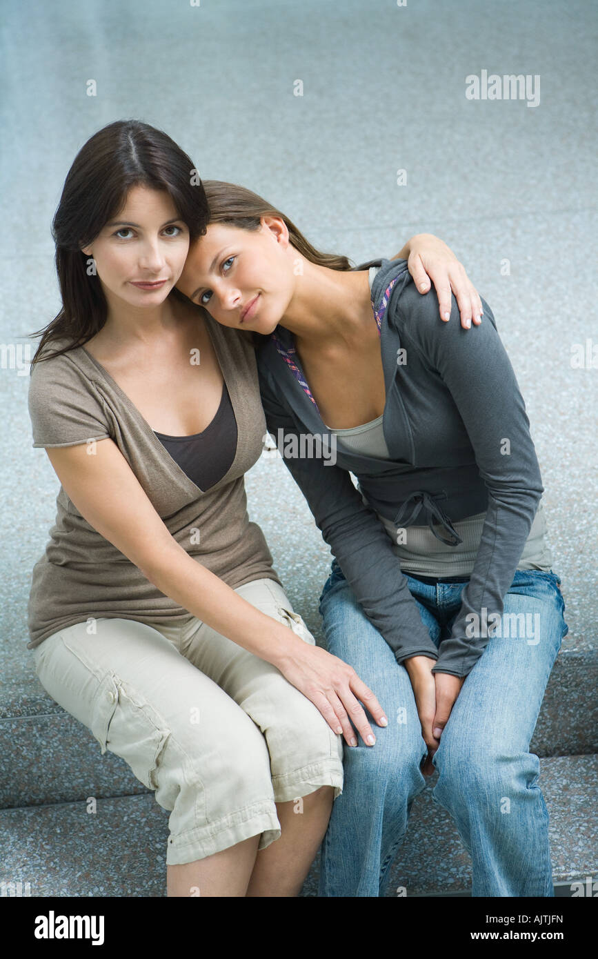 Mother and teenage girl sitting side by side, teen girl resting head on