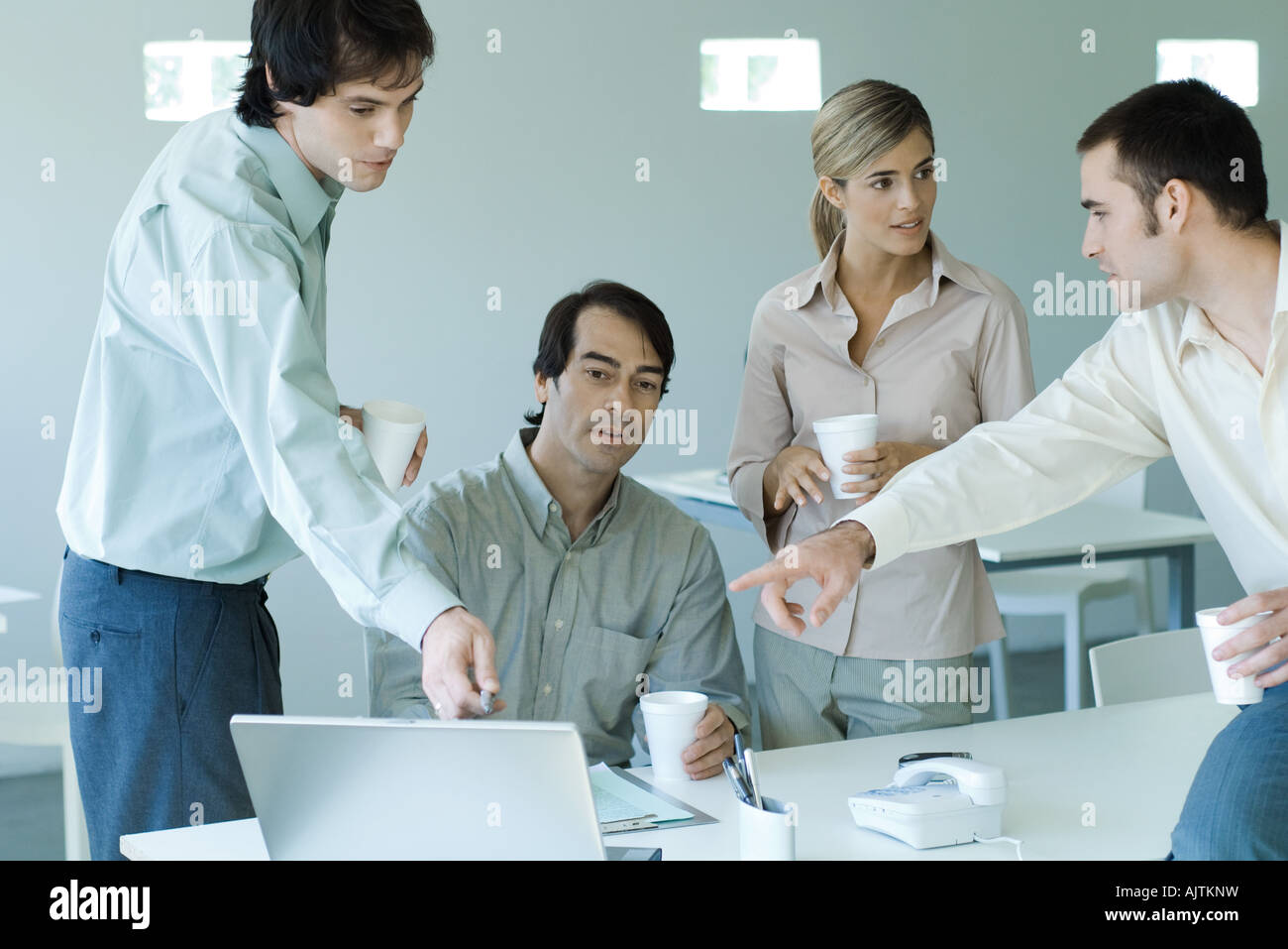 Business associates gathered around laptop, two pointing to screen Stock Photo