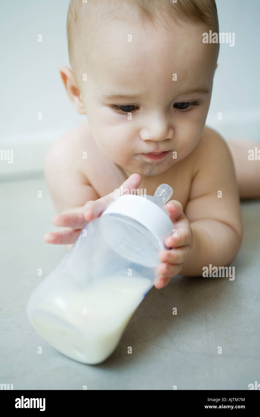 Baby lying on floor, holding bottle Stock Photo Alamy