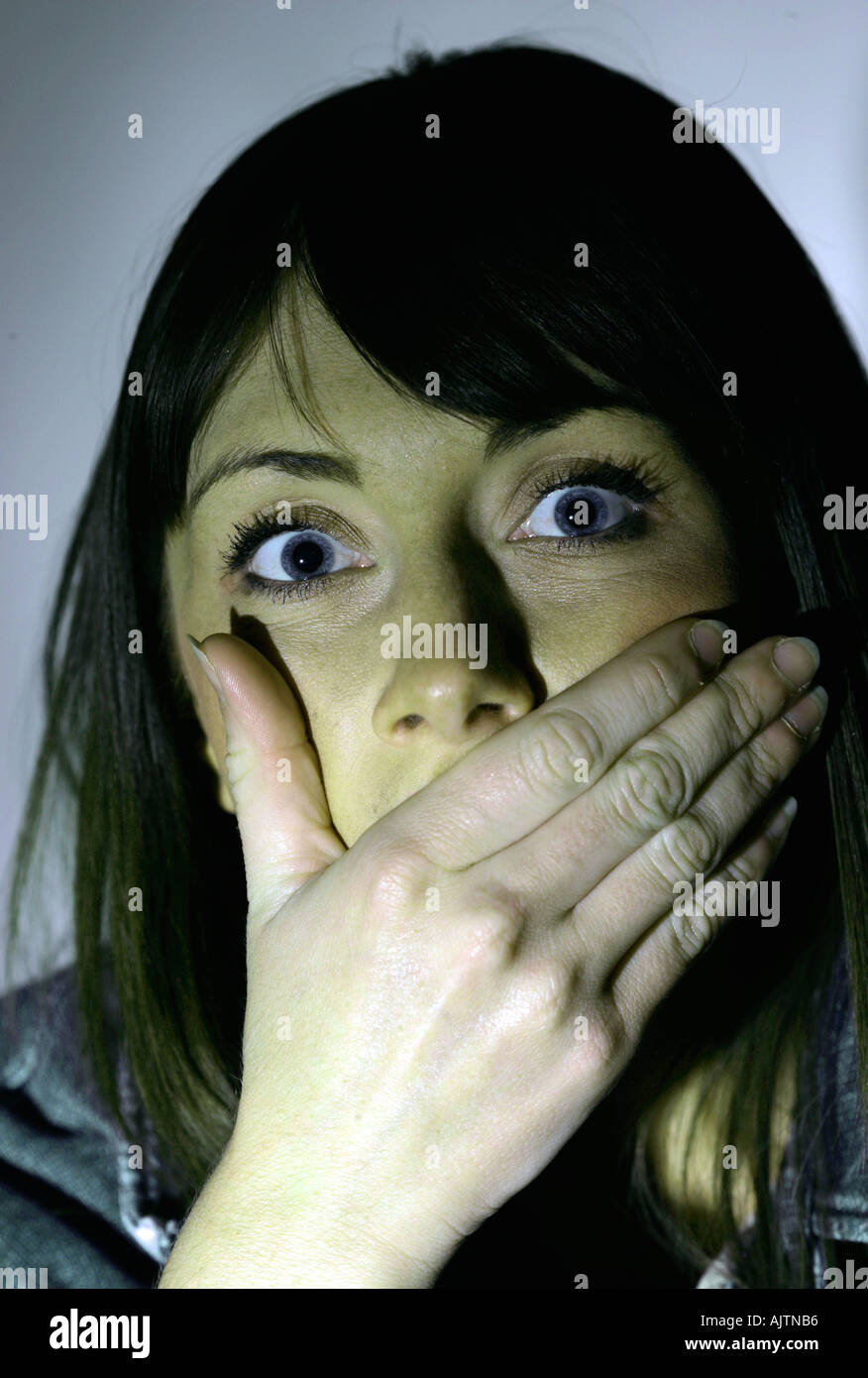 Young woman with brown hair holding her hand to her face Stock Photo