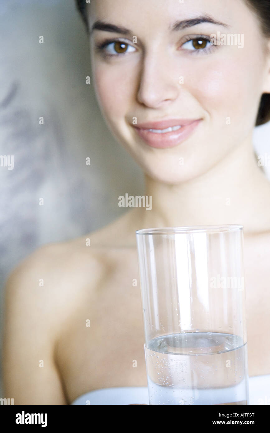 Young woman holding glass of water, smiling at camera Stock Photo - Alamy
