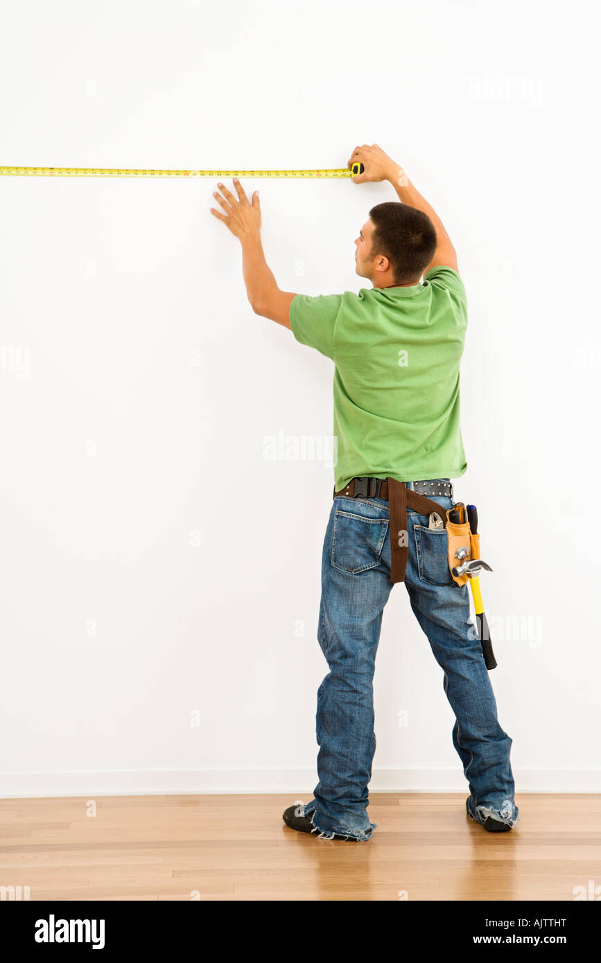 Man wearing tool belt measuring interior wall Stock Photo Alamy