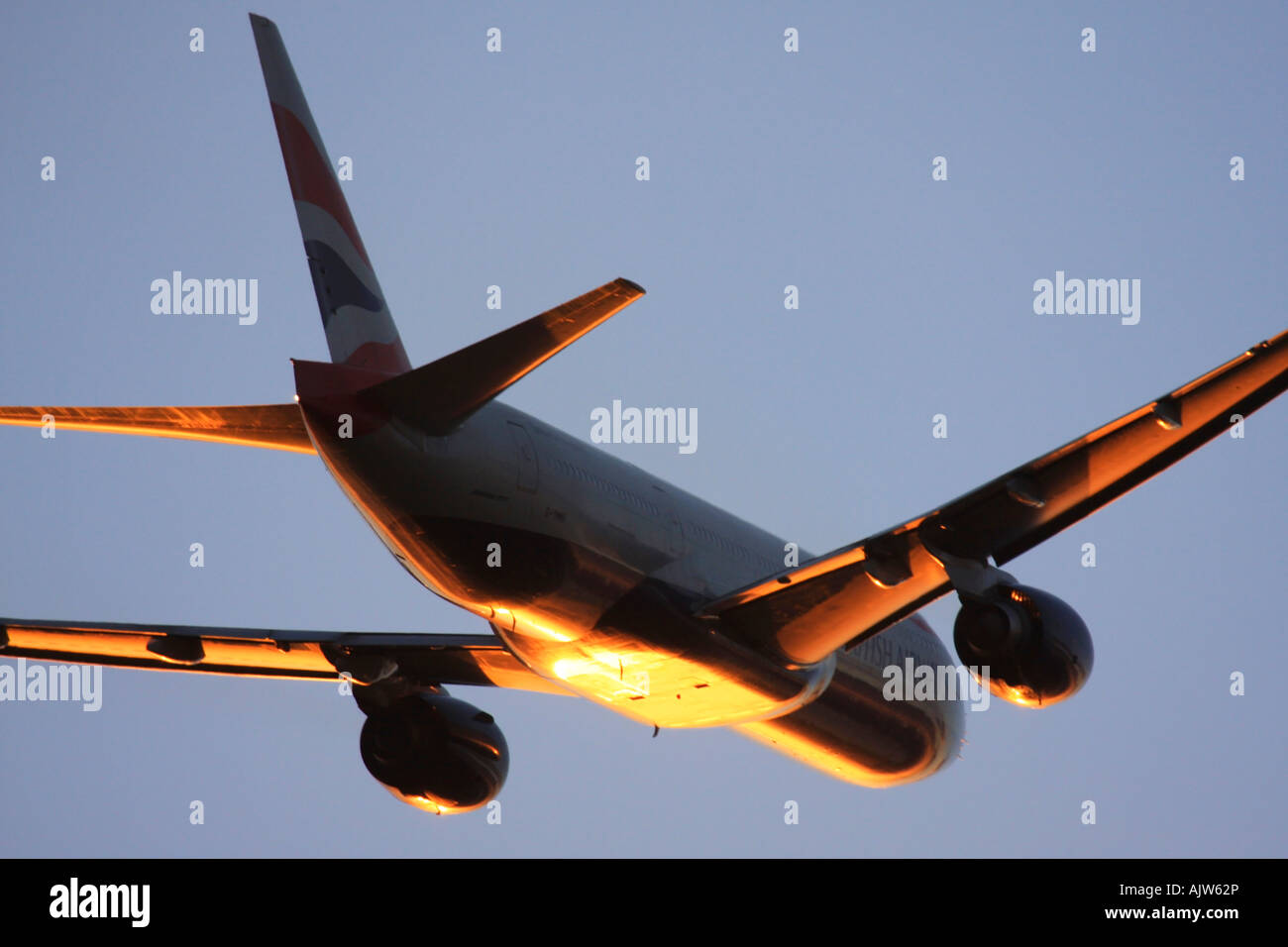 British Airways Boeing 777 just after take off in reflecting sunset light at Heathrow Airport, London, England, UK. Stock Photo