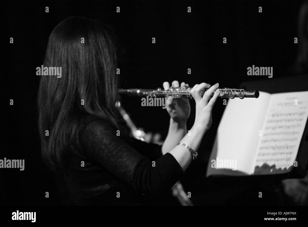 A girl plays the flute at a school concert. Black and white image Stock Photo