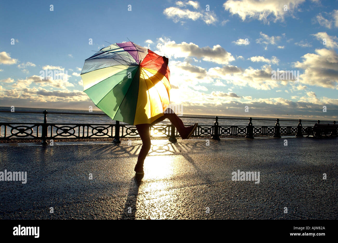 Dancing with the wind. A girl with a brightly coloured brolly on Brighton seafront on a windy day Stock Photo