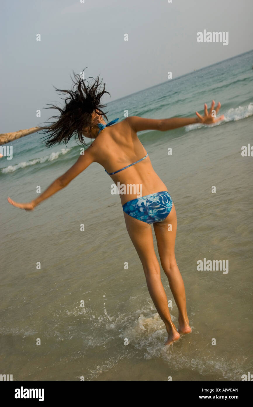 Girl Sunbathing and jumping on the beach Stock Photo