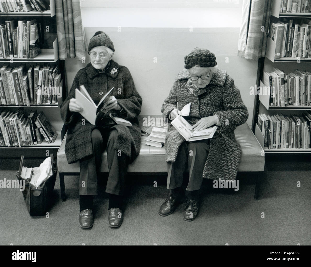 1980 scene of two women pensioners studying books in library, Malmesbury, UK. Stock Photo