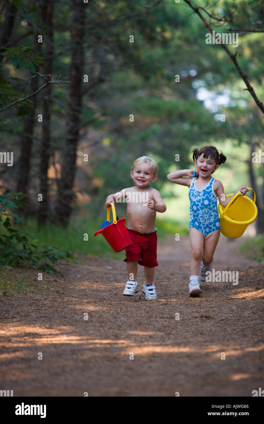 Brother and sister running on forest path Stock Photo - Alamy