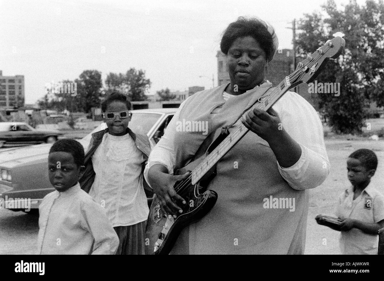 Black woman playing blues guitar while her three boys watch, Maxwell Street, Chicago, U.S.A Stock Photo
