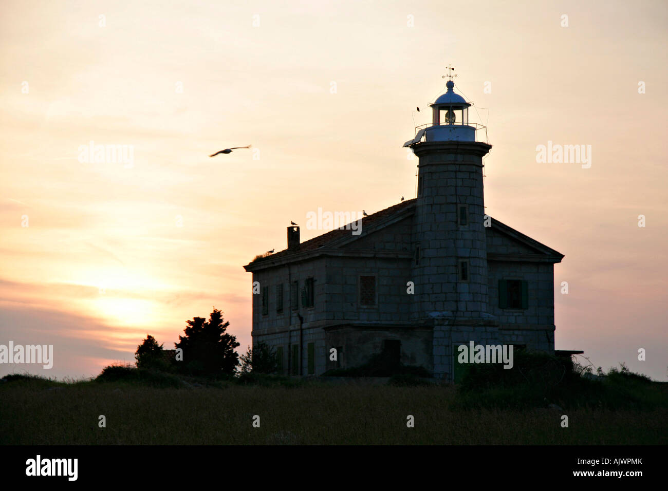 alter Leuchtturm auf der einsamen Insel Trstenik im Sonnenuntergang | old lighthouse on lonely island Trstenik in the sunset Stock Photo