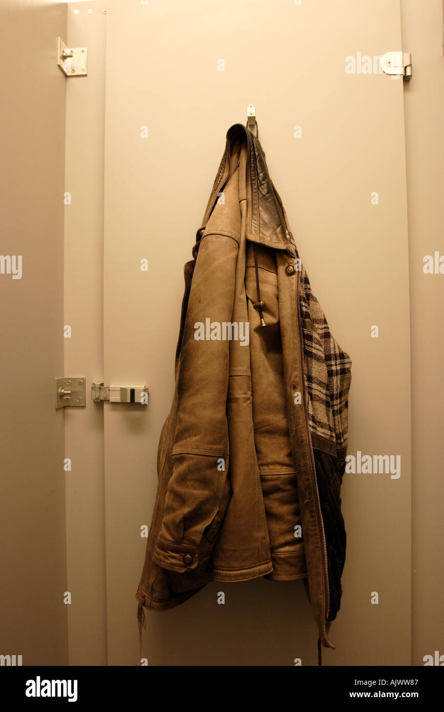 Coat hanging on the back of the door of a public toilet cubicle Stock Photo