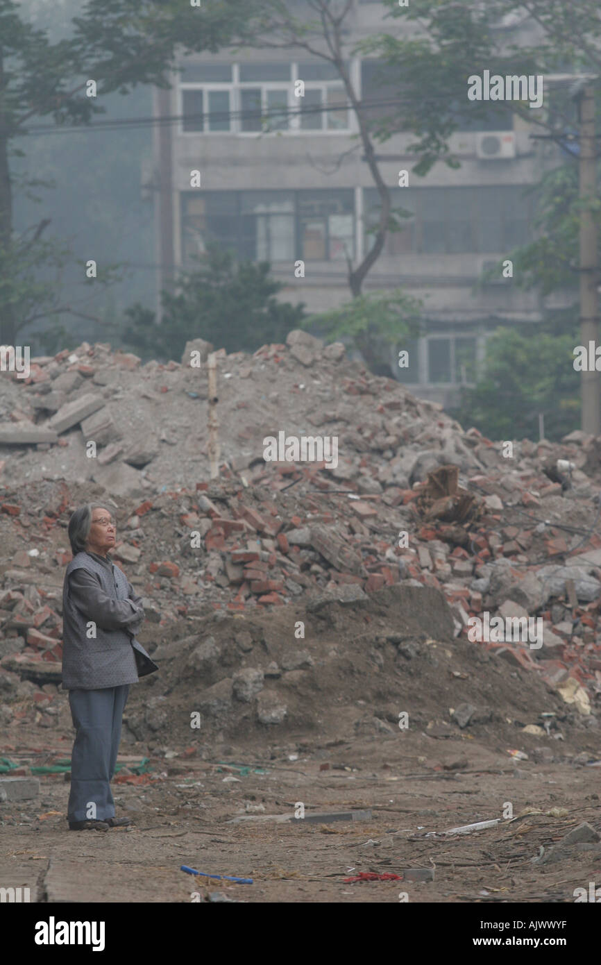 An old woman surveys the remains of the neighbourhood she still lives in as it is demolished in central Beijing. Stock Photo