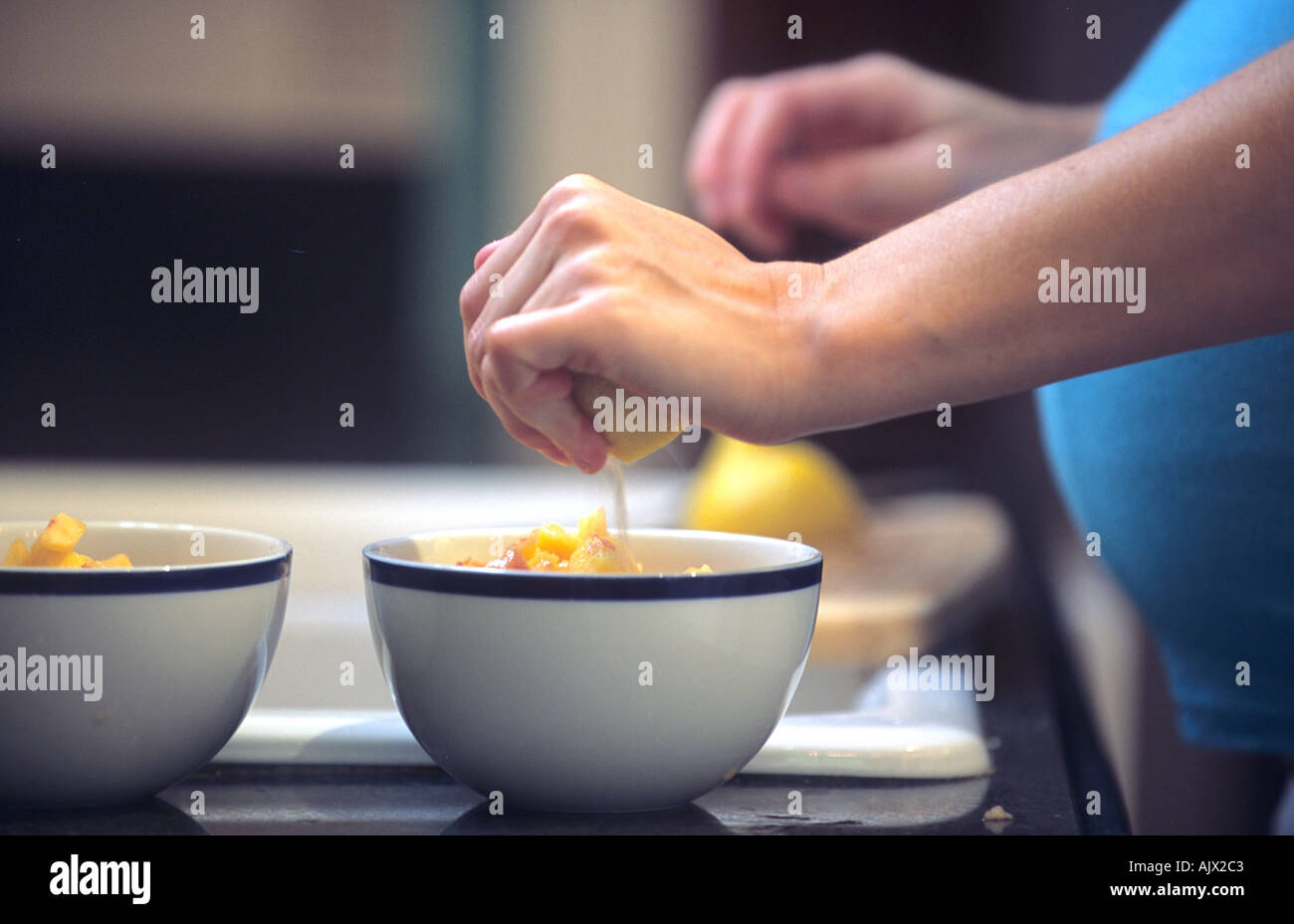 Pregnant woman squeezes lemon juice on her bowl of fruit Stock Photo Alamy