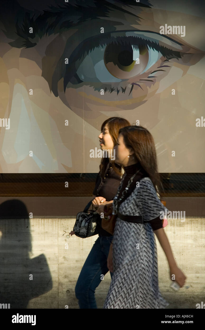 Two young women walking by a manga style poster on Omotosando in Harajuku, Tokyo Japan Stock Photo