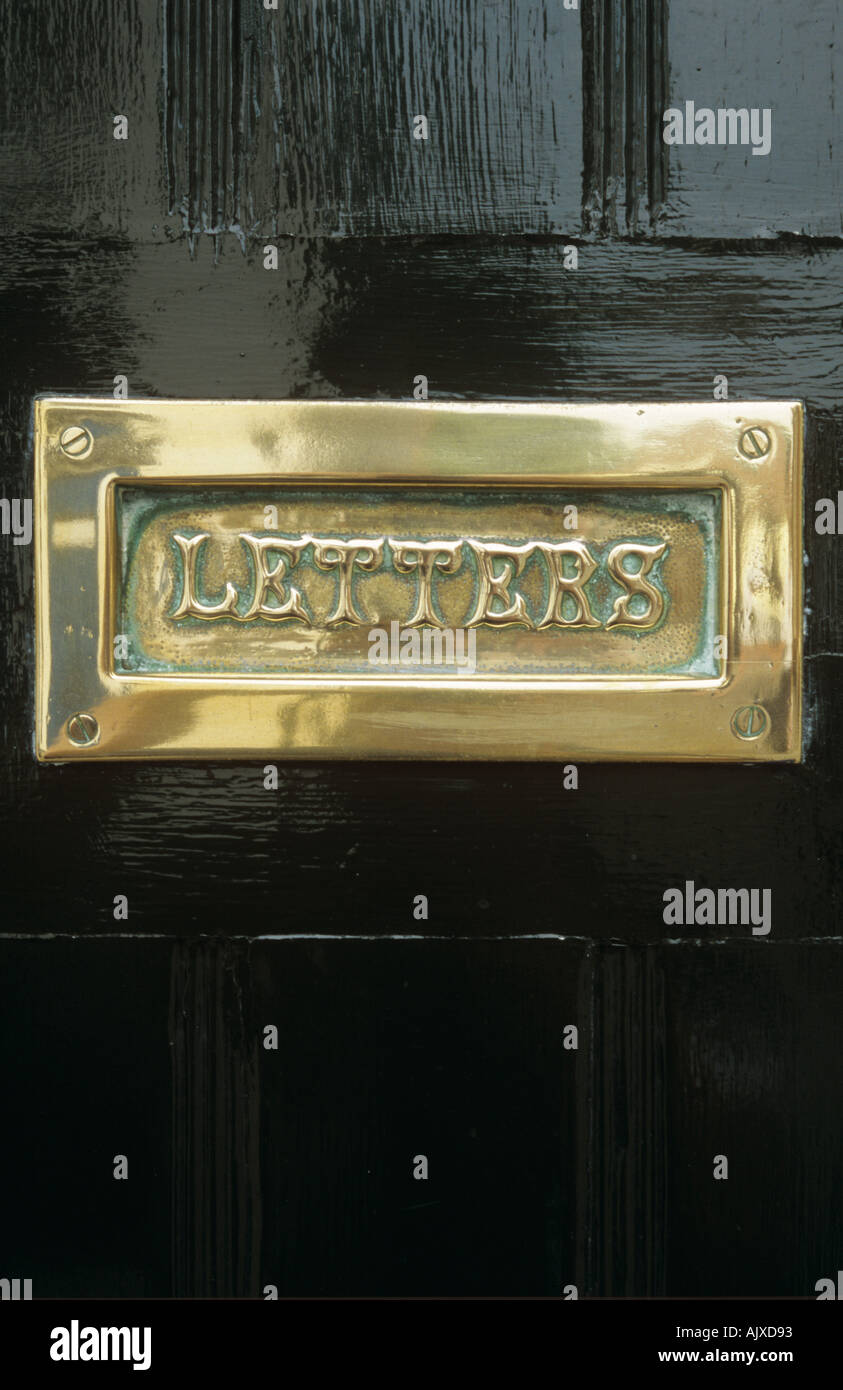Polished brass letterbox in black front door Stock Photo Alamy