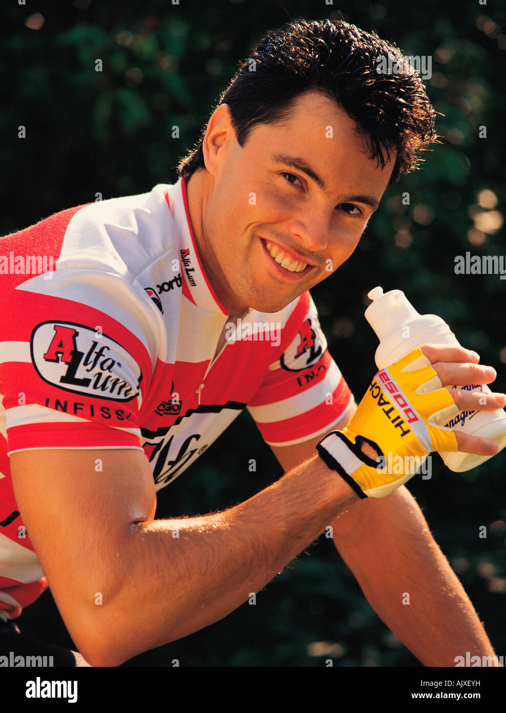 Outdoor portrait of young man cyclist close-up with bottle of drink. Stock Photo