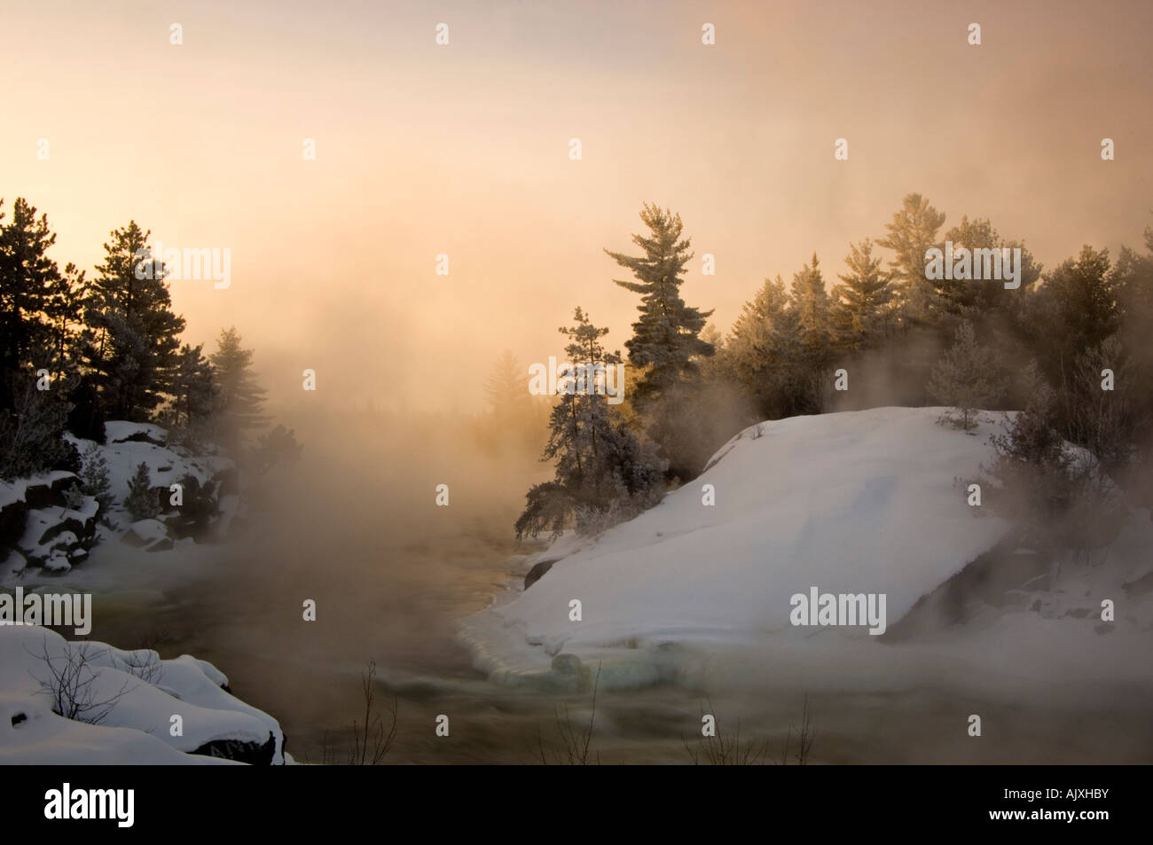 Tree silhouettes and rising mists near rapids of Wanapitei River at sunrise, Greater Sudbury, Ontario, Canada Stock Photo