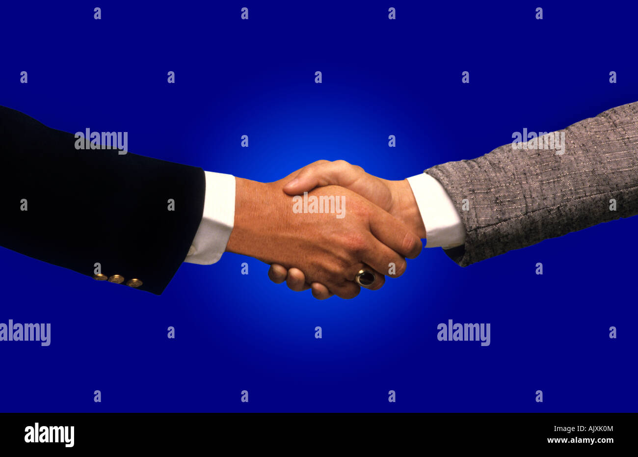 Two businessmen shaking hands with blue background closing deal Stock Photo