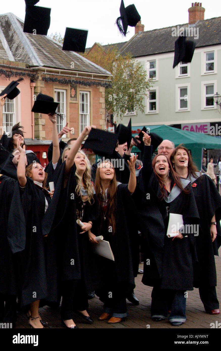 Group of happy student and staff throwing hats into air after