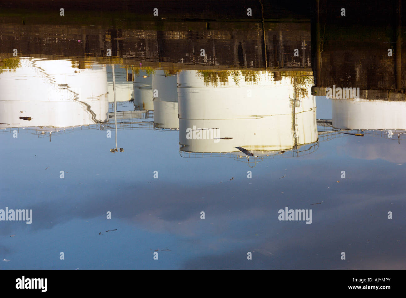 Reflection in water of fuel storage tanks at Rothsay Dock East, Glasgow with rubbish on surface of water Stock Photo