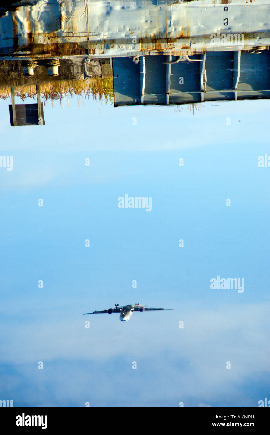 Reflection in water of aircraft coming in to land at Glasgow airport Stock Photo