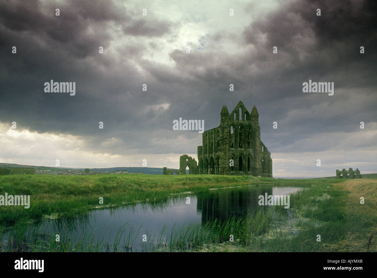 Whitby Abbey reflected in the pond and silhouetted against a stormy sky Stock Photo