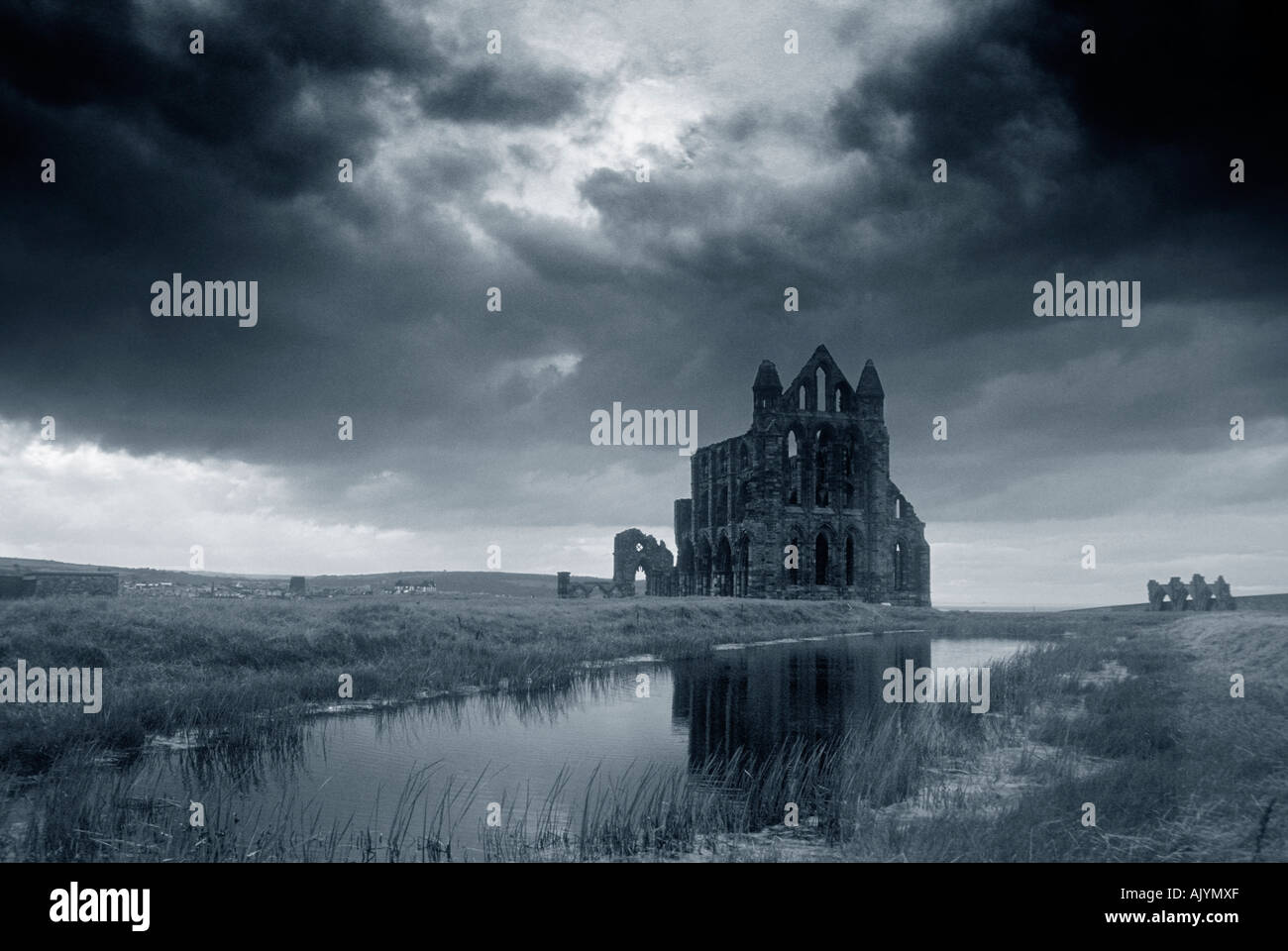 Whitby Abbey reflected in the pond and silhouetted against a stormy sky Stock Photo